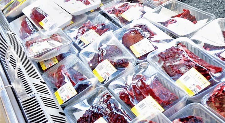 Various cuts of dolphin meat are packaged in plastic and displayed for sale on a supermarket shelf. Each package has a yellow price label. The presentation suggests the meat may be from a dolphin drive hunt, which is controversial and often debated in terms of ethics and sustainability.