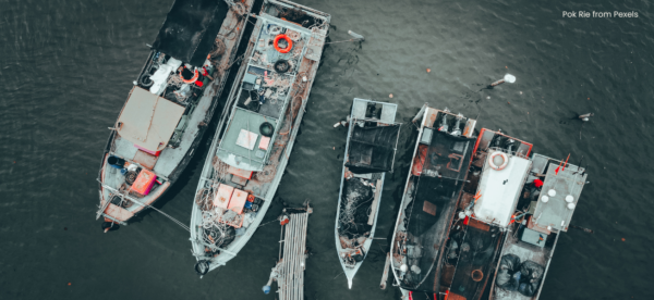Five fishing vessels in the ocean being seen from a birds eye view