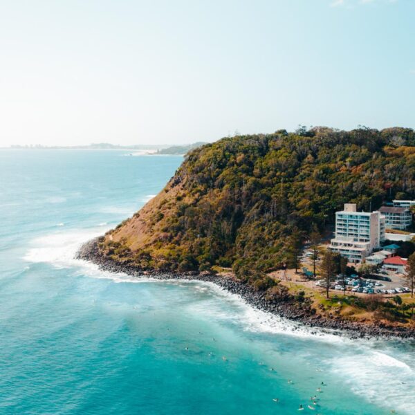 Green flat ocean pushes against a cliff with tourist multi story buildings nestled against it
